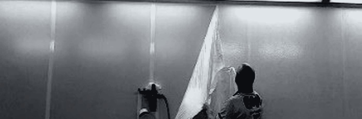 A technician applying peelable booth-wall coating